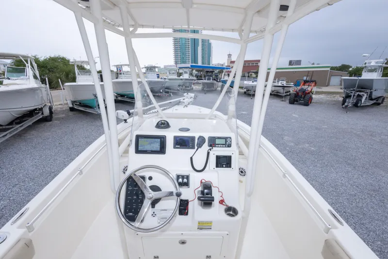 Slide: The Image of 2016 Cobia 201 Center Console boat dashboard with navigation equipment in a marina setting. - 28