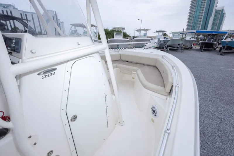 Slide: The Image of 2016 Cobia 201 Center Console boat with spacious seating, docked near modern buildings. - 29