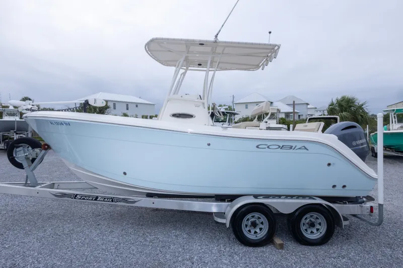 Slide: The Image of 2016 Cobia 201 Center Console boat on trailer, side view, in a coastal setting. - 4