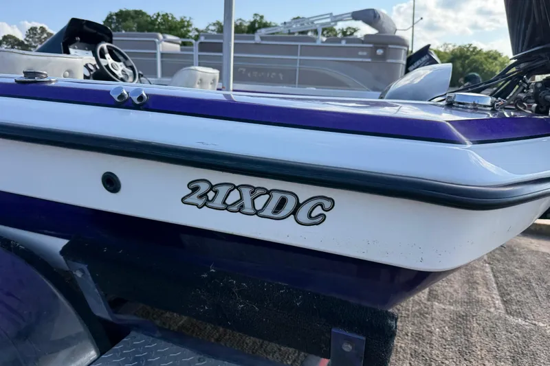 Slide: The Image of 2002 Bullet 21XDC boat with purple and white exterior, parked outdoors. - 15