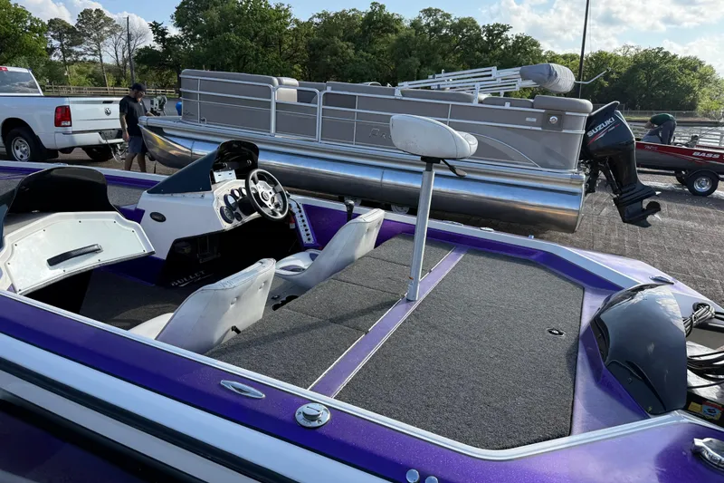Slide: The Image of Purple 2002 Bullet 21XDC boat interior with steering wheel, parked near pontoon and truck. - 16
