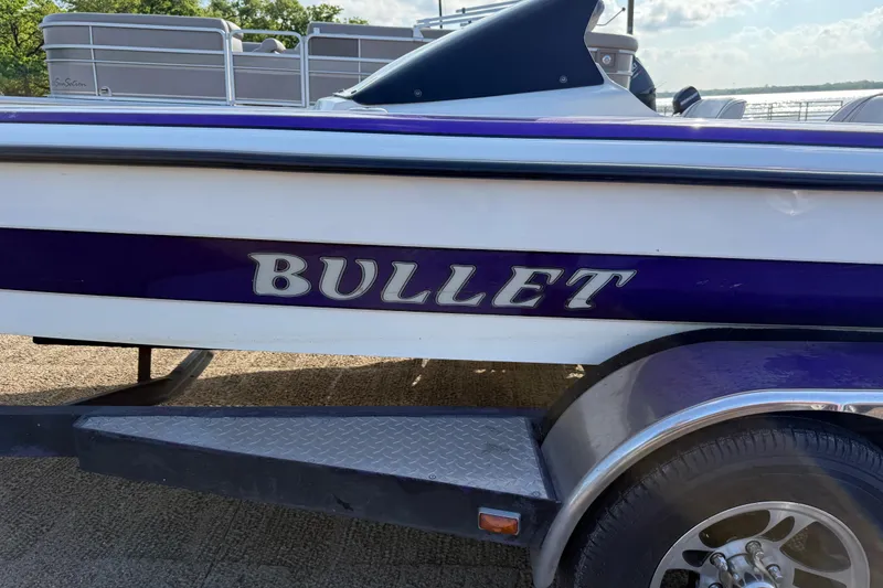 Slide: The Image of 2002 Bullet 21XDC boat with purple and white design on trailer. - 19