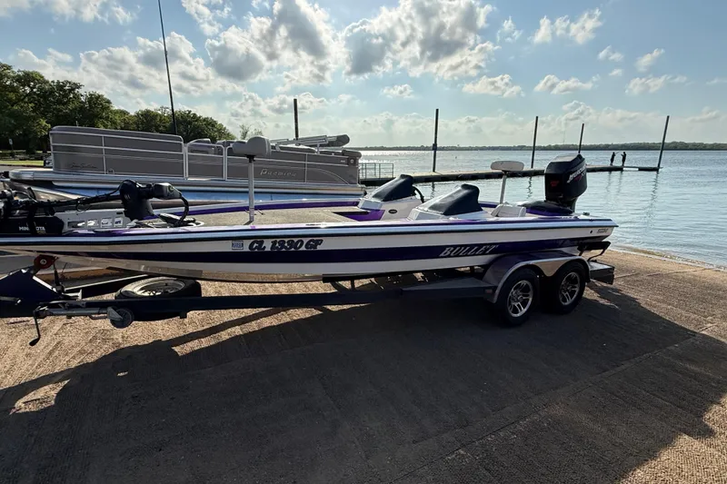 Slide: The Image of 2002 Bullet 21XDC boat on trailer by lake, under a partly cloudy sky. - 20
