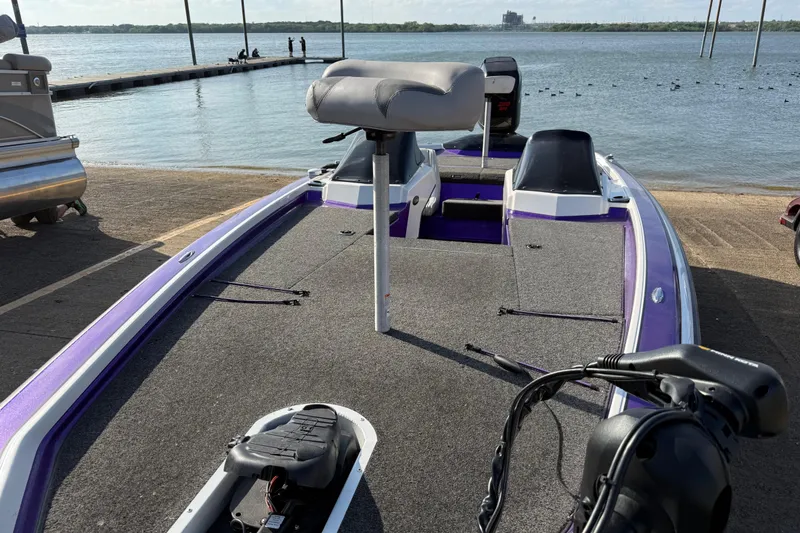 Slide: The Image of 2002 Bullet 21XDC boat with purple accents docked by a serene lake. - 24