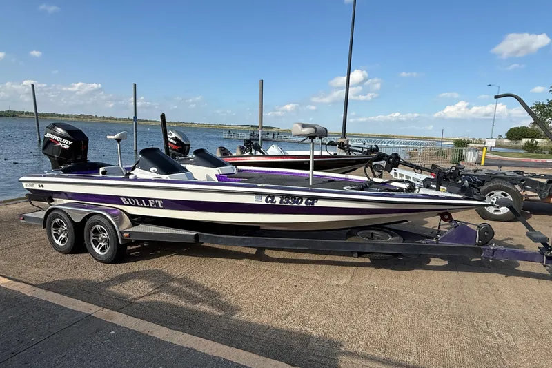 Slide: The Image of 2002 Bullet 21XDC boat on trailer by the water, featuring Mercury engine. - 4