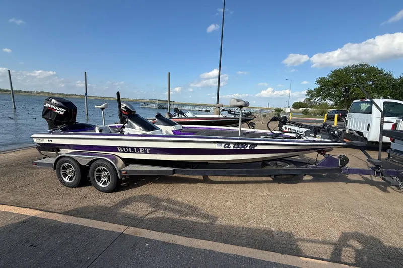 Slide: The Image of 2002 Bullet 21XDC boat on trailer by lakeside, featuring Mercury outboard motor. - 5