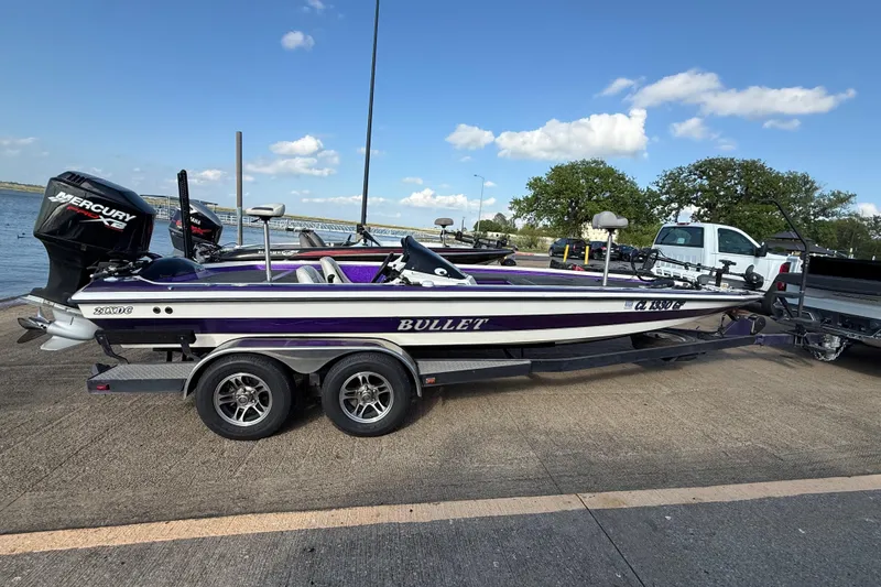 Slide: The Image of 2002 Bullet 21XDC boat with Mercury engine on trailer by a lake. - 7