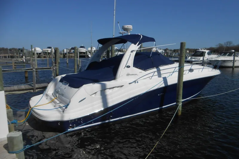 The Image of 2005 Sea Ray 340 Sundancer docked at marina, featuring sleek design and blue cover. - 0