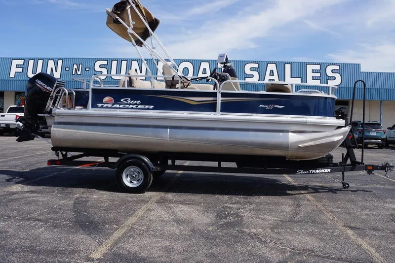 The Image of 2025 Sun Tracker Bass Buggy 18 DLX pontoon boat at dealership, on trailer. - 0