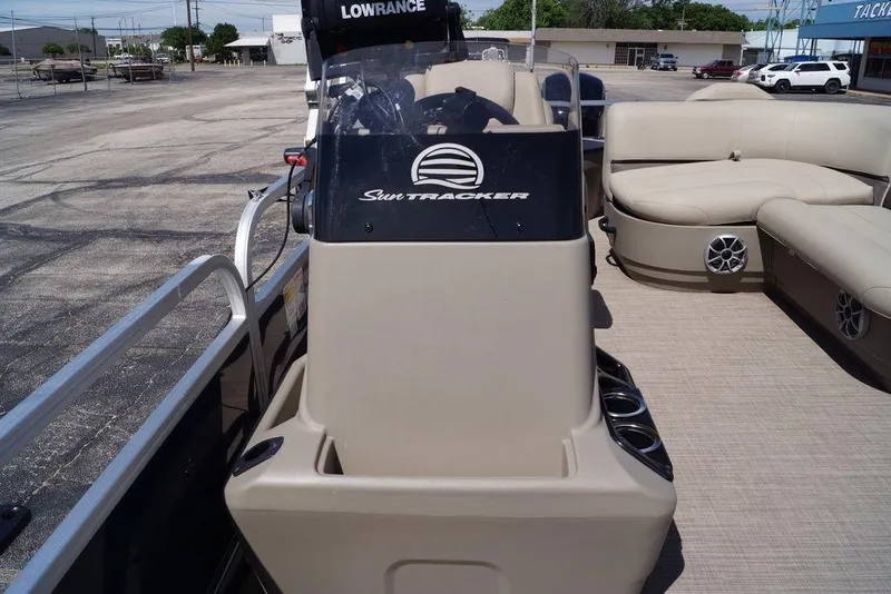 Slide: The Image of 2025 Sun Tracker Bass Buggy 18 DLX pontoon boat with beige seating and steering console. - 12