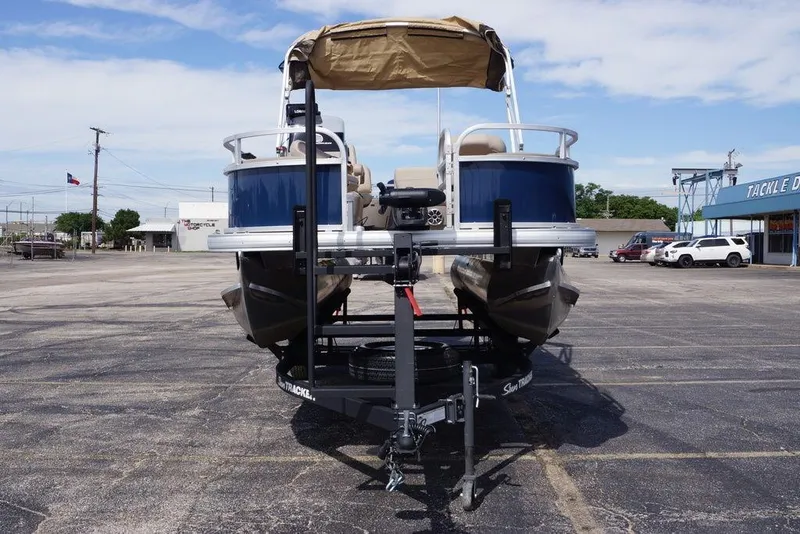 Slide: The Image of 2025 Sun Tracker Bass Buggy 18 DLX pontoon boat on trailer in parking lot. - 4