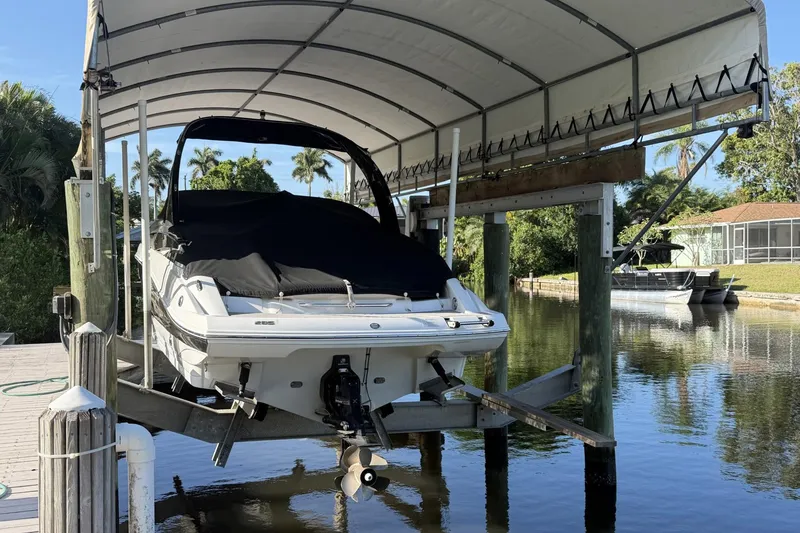 Slide: The Image of 2013 Crownline 285 SS boat on lift under canopy by waterfront dock. - 2