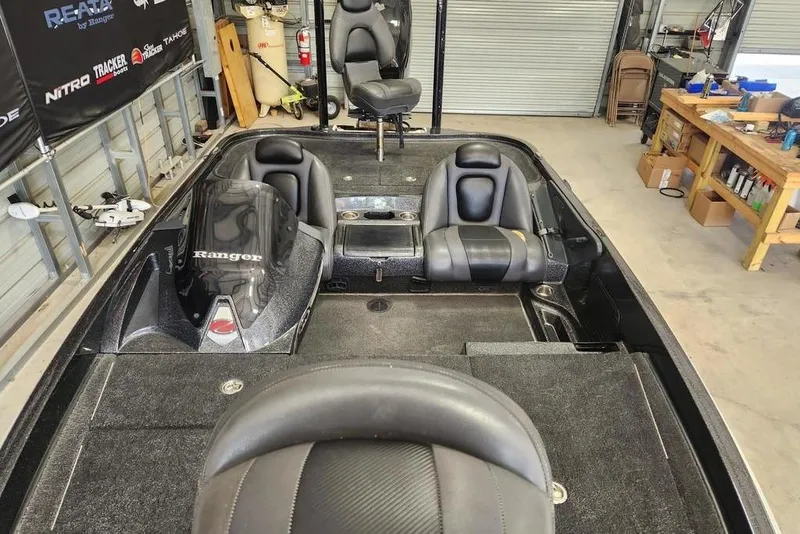 Slide: The Image of 2013 Ranger Z518 Comanche boat interior in a garage, featuring seating and storage compartments. - 5