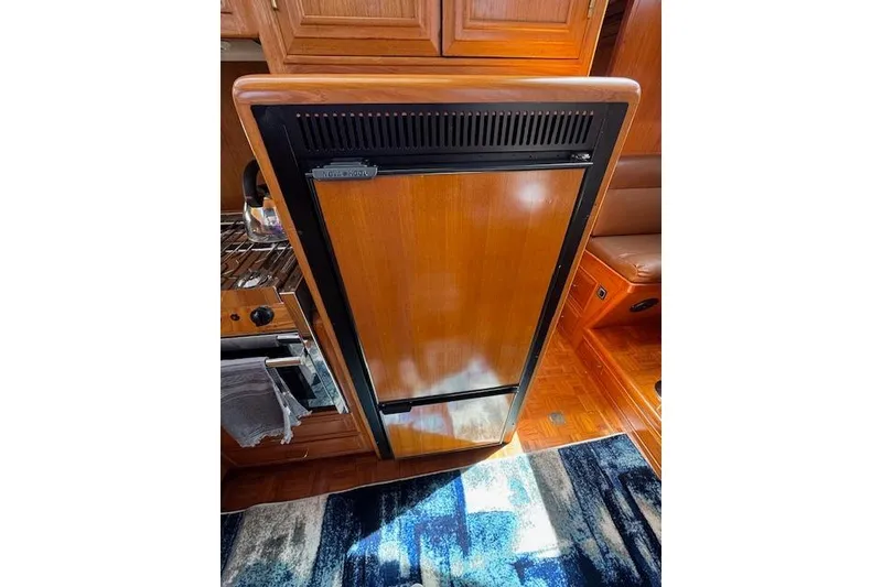 Slide: The Image of Wooden interior of 1993 Ocean Alexander 440 Sundeck CPMY yacht, featuring a built-in refrigerator. - 23