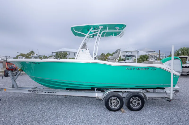 Slide: The Image of 2023 Key West 239 FS boat on trailer, vibrant teal color, parked outdoors. - 16