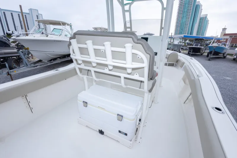 Slide: The Image of 2023 Key West 239 FS boat interior with seating and rod holders, docked near modern buildings. - 28