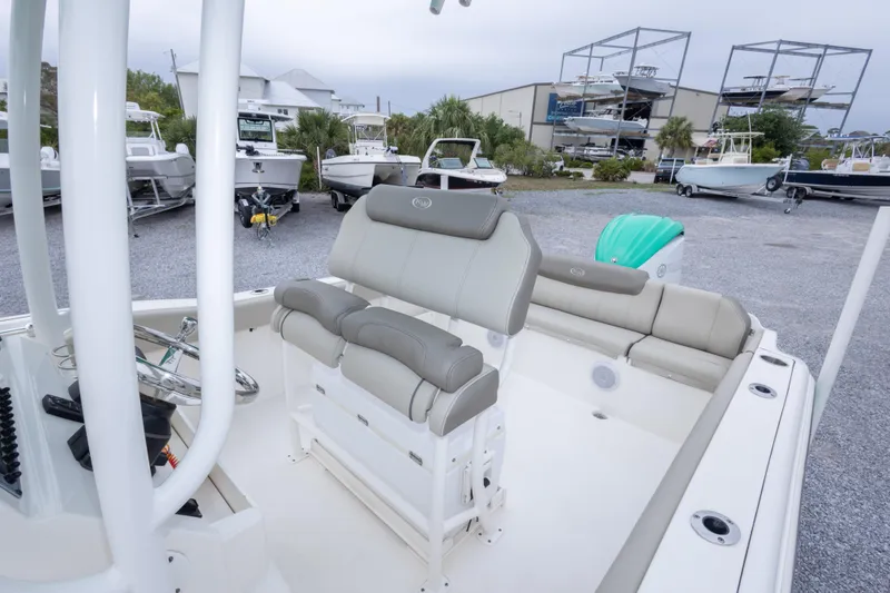 Slide: The Image of 2023 Key West 239 FS boat interior with seating and steering wheel, in a marina setting. - 45