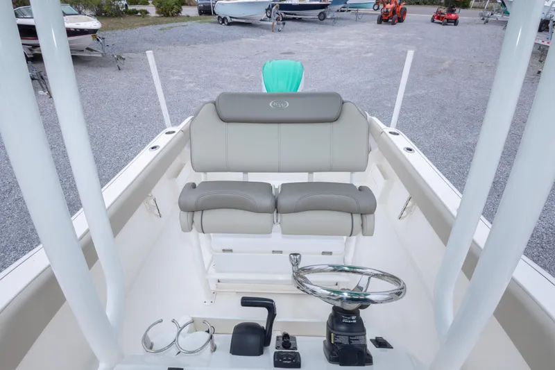 Slide: The Image of 2023 Key West 239 FS boat interior with steering wheel and seating in a marina setting. - 47