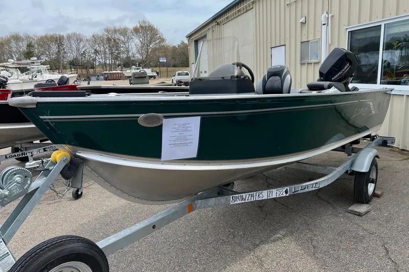 Slide: The Image of 2026 Lund 1400 Fury SS boat on trailer, green exterior, parked outdoors. - 16