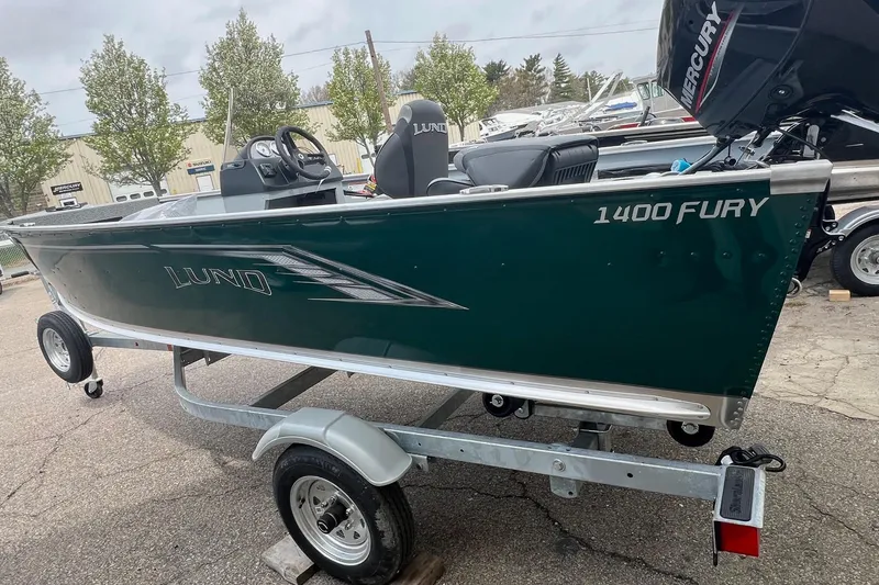 Slide: The Image of 2026 Lund 1400 Fury SS boat on trailer, green exterior, parked outdoors. - 4