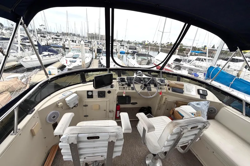 Slide: The Image of 1989 45' Californian Aft Cabin Motor Yacht helm with marina view, featuring dual captain chairs. - 13