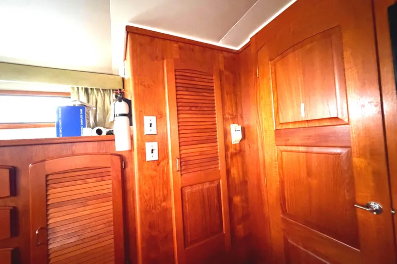 Slide: The Image of Interior of 1989 45' Californian Aft Cabin Motor Yacht with wooden cabinetry and fire extinguisher. - 37