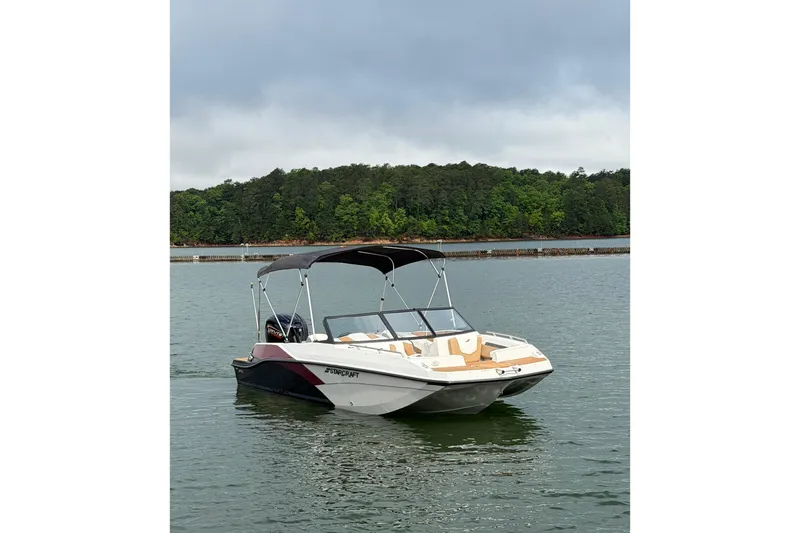 The Image of 2023 Starcraft SVX 210 DC OB boat on a serene lake with lush green trees. - 1