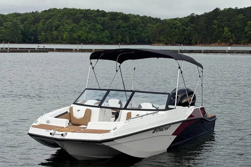 Slide: The Image of 2023 Starcraft SVX 210 DC OB boat on a serene lake with lush green forest backdrop. - 15