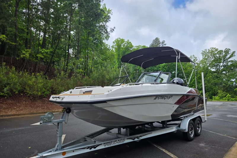 Slide: The Image of 2023 Starcraft SVX 210 DC OB boat on trailer in wooded parking area. - 17
