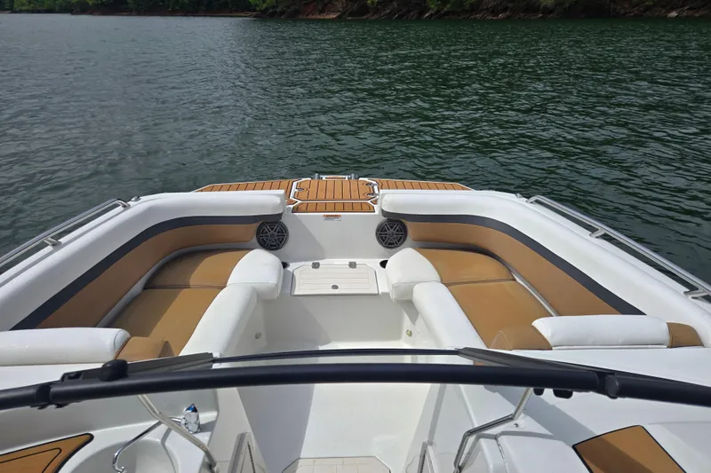 Slide: The Image of 2023 Starcraft SVX 210 DC OB boat interior with tan and white seating on a lake. - 7