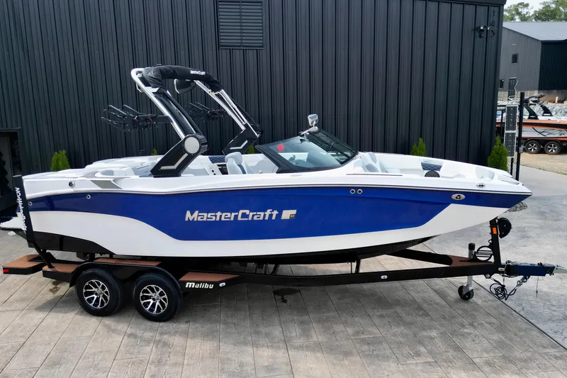 Slide: The Image of 2023 MasterCraft XT22 boat in blue and white on a trailer, parked outdoors. - 15