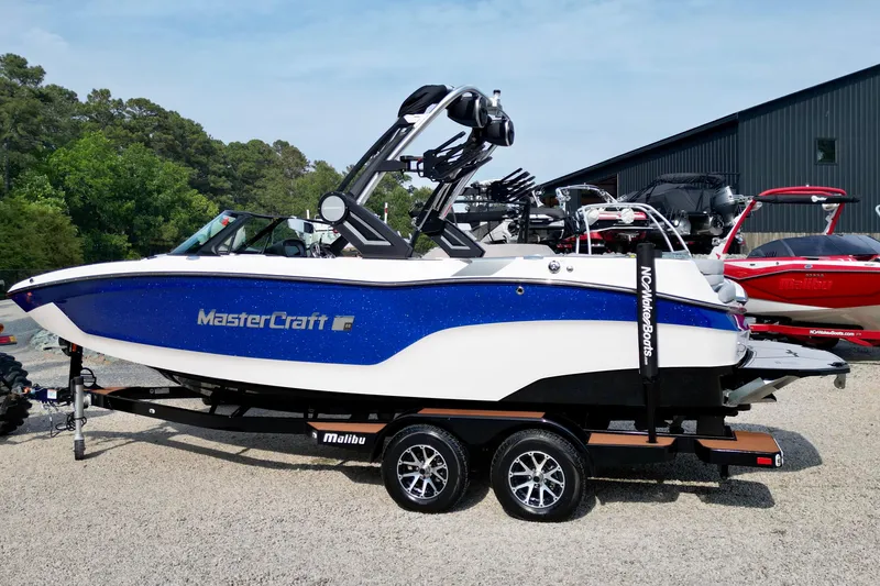 Slide: The Image of 2023 MasterCraft XT22 boat with blue and white design on a trailer. - 2