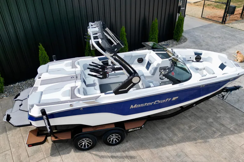 Slide: The Image of 2023 MasterCraft XT22 boat with sleek design, blue and white color scheme, parked on a trailer. - 4