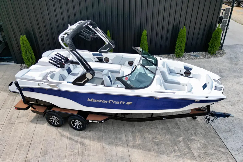 Slide: The Image of 2023 MasterCraft XT22 boat with sleek design, blue and white color, on a trailer. - 5