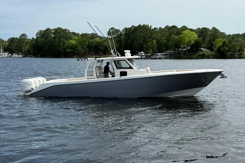 The Image of 2022 Solace 41CS boat cruising on a serene lake with lush green trees. - 0