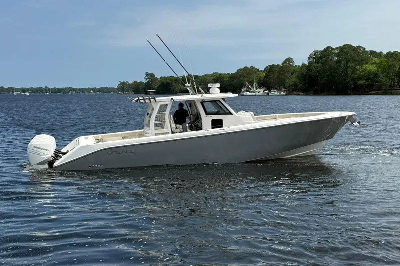 Slide: The Image of 2022 Solace 41CS boat cruising on a serene lake with lush green shoreline. - 2