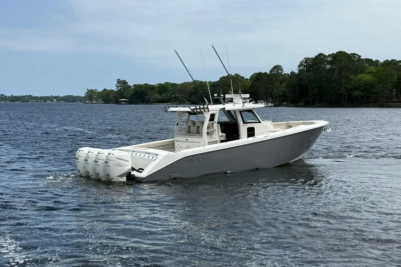 Slide: The Image of 2022 Solace 41CS boat cruising on a serene lake with forested shoreline. - 3