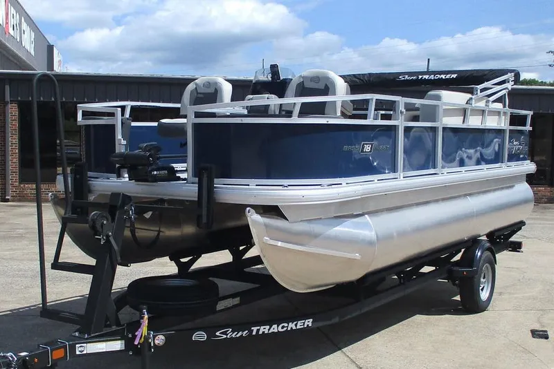 Slide: The Image of 2026 Sun Tracker Bass Buggy 18 DLX pontoon boat on trailer, parked outdoors. - 10