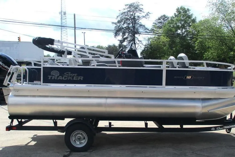 Slide: The Image of 2026 Sun Tracker Bass Buggy 18 DLX pontoon boat on trailer, parked outdoors. - 7