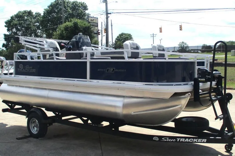 Slide: The Image of 2026 Sun Tracker Bass Buggy 18 DLX pontoon boat on trailer, parked outdoors. - 8
