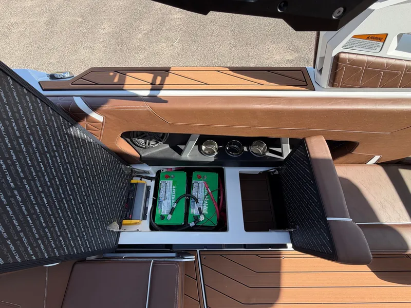 Slide: The Image of The image shows the battery compartment of a 2027 Nautique GS22 SUPER AIR with brown upholstery. - 33