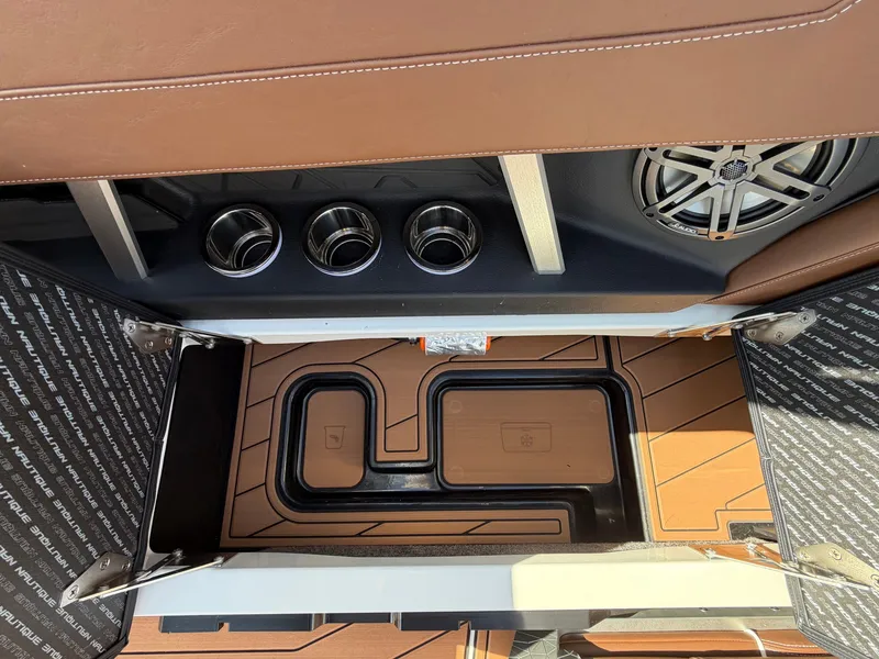 Slide: The Image of Interior view of a 2027 Nautique GS22SUPER AIR with brown upholstery and cup holders. - 38