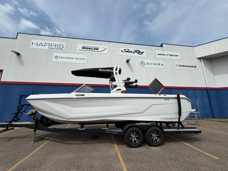 Slide: The Image of A white boat on a trailer in front of a building with various boat brand logos. - 0