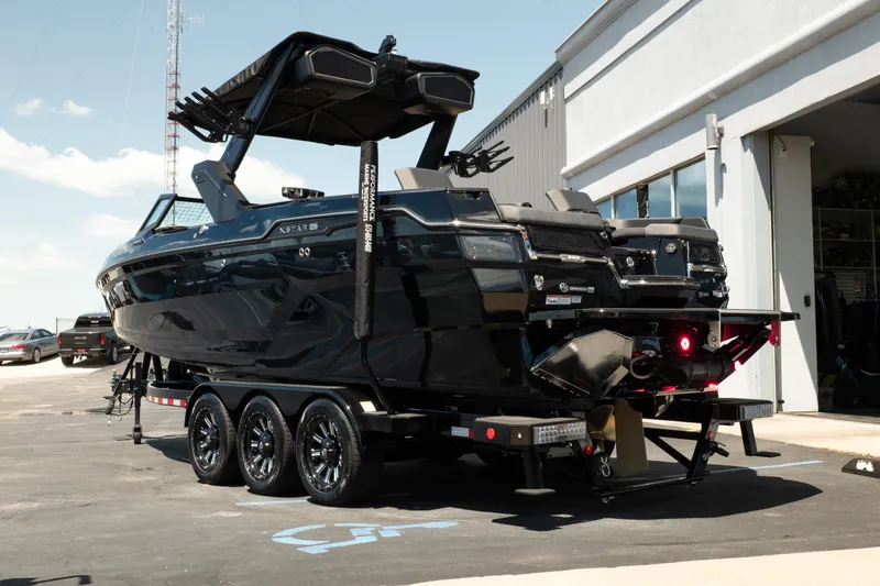 Slide: The Image of 2026 MasterCraft XStar 25 boat on trailer, parked outside a building. - 11
