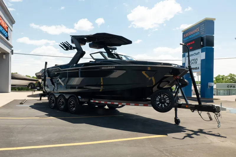 Slide: The Image of 2026 MasterCraft XStar 25 boat on trailer at dealership under clear sky. - 17
