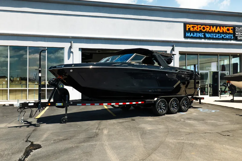 Slide: The Image of 2026 MasterCraft XStar 25 boat on trailer outside Performance Marine Watersports showroom. - 2