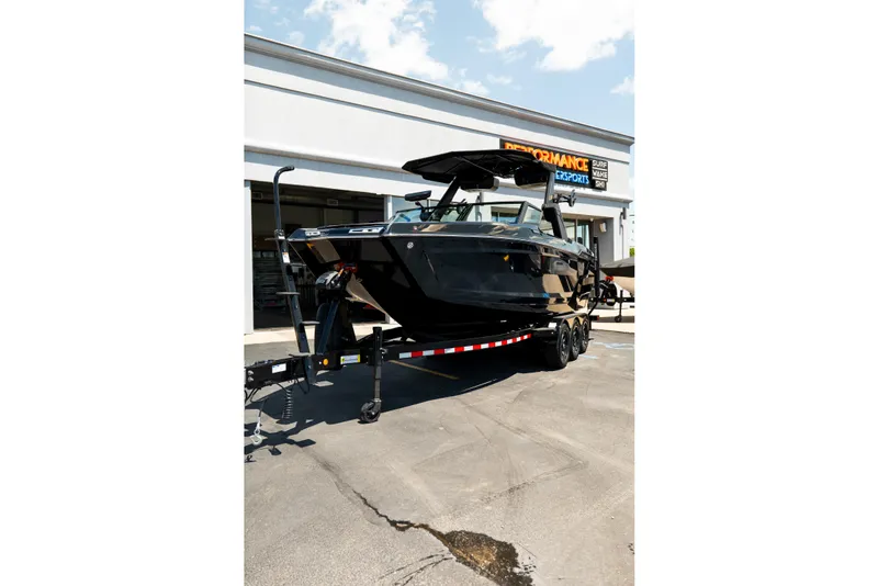 Slide: The Image of 2026 MasterCraft XStar 25 boat on trailer outside dealership, showcasing sleek black design. - 55