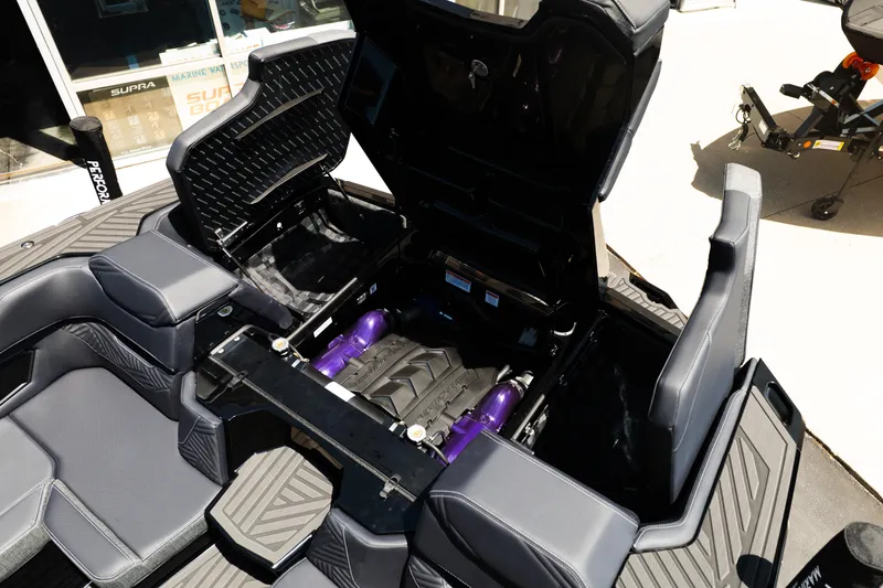 Slide: The Image of 2026 MasterCraft XStar 25 boat interior with open engine compartment, showcasing sleek design and seating. - 57