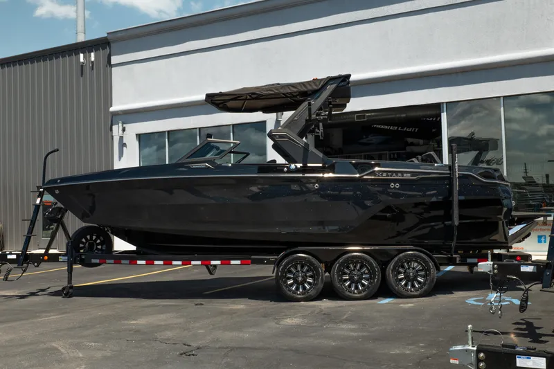 Slide: The Image of 2026 MasterCraft XStar 25 boat on trailer, parked outside a building. - 7