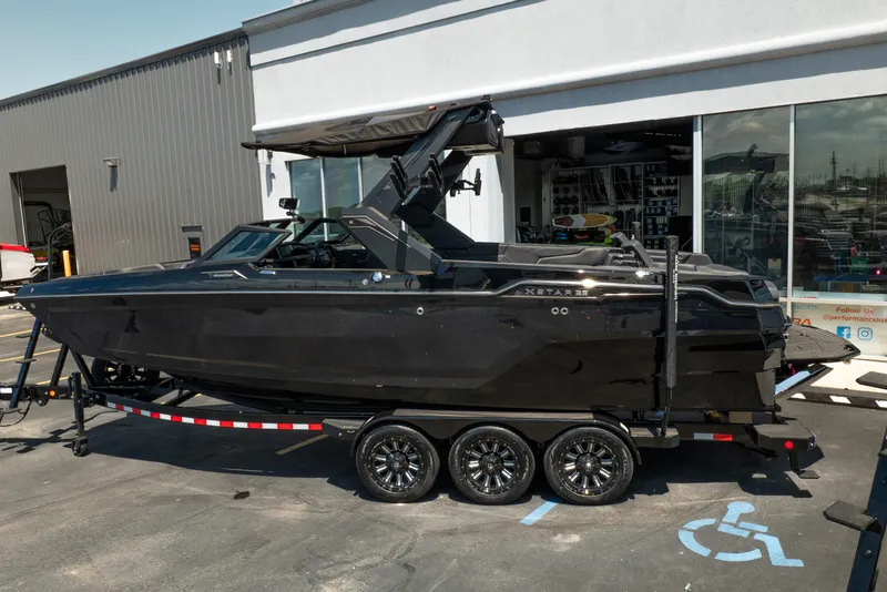 Slide: The Image of 2026 MasterCraft XStar 25 boat on trailer, parked outside a showroom. - 8